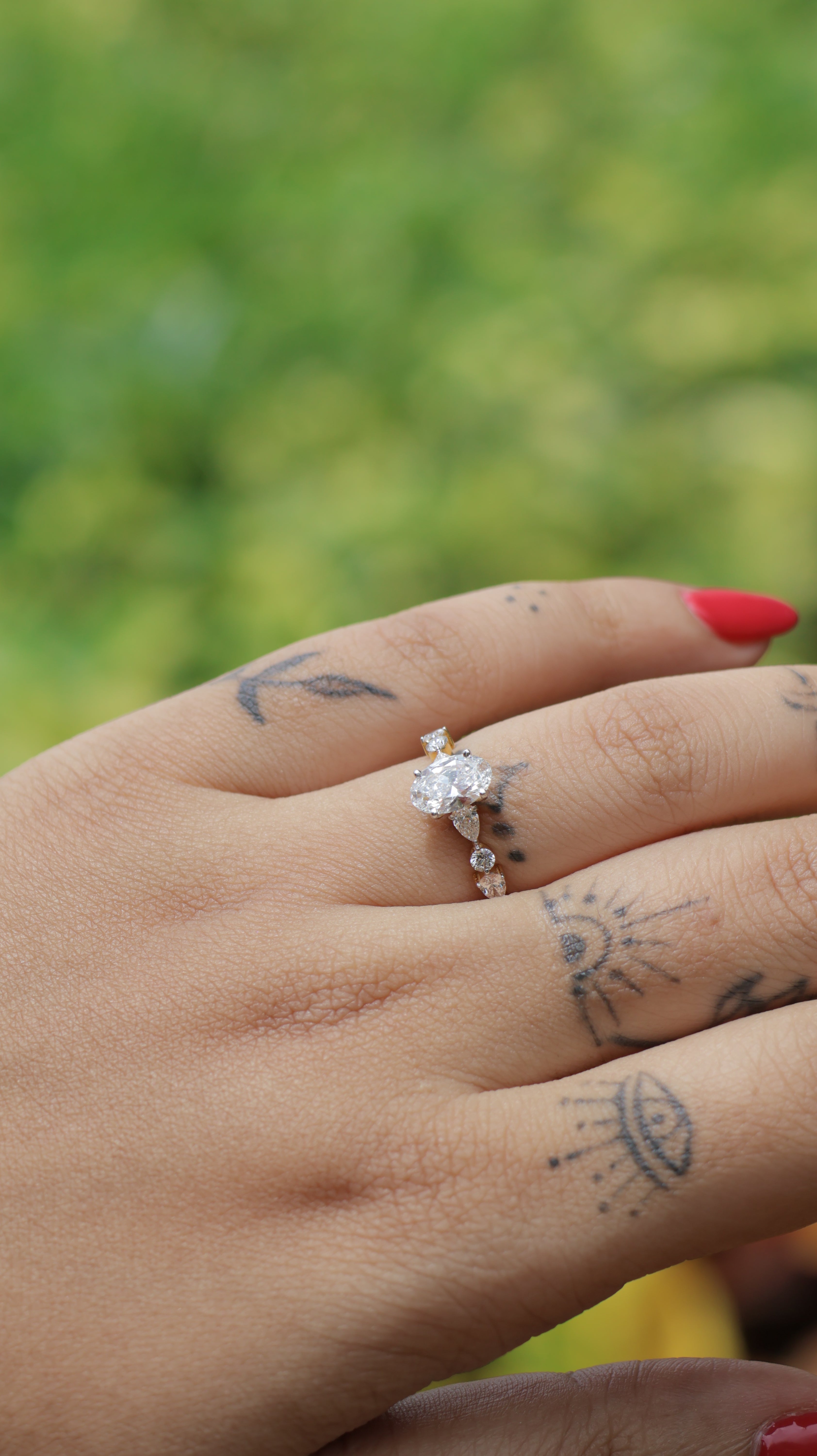 Close-up of a hand with a diamond ring on a blurred green background